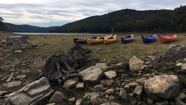 Kayaks lined up on a lake shore for a GRAB trip.